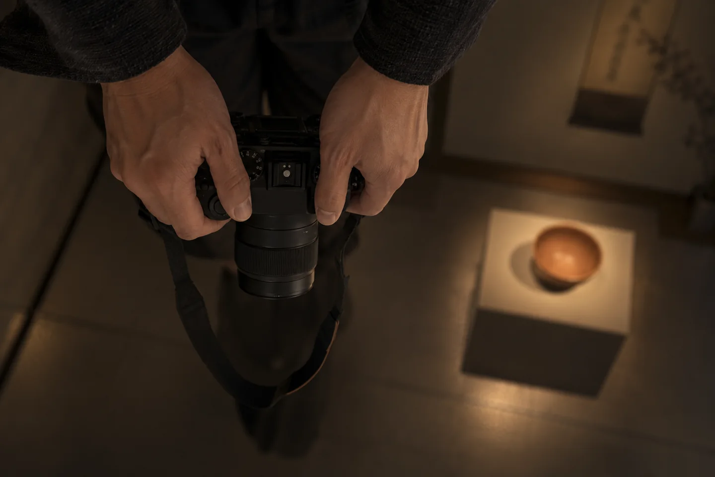 Adult holds a plain camera pointed downward beside undecorated clay vessels
