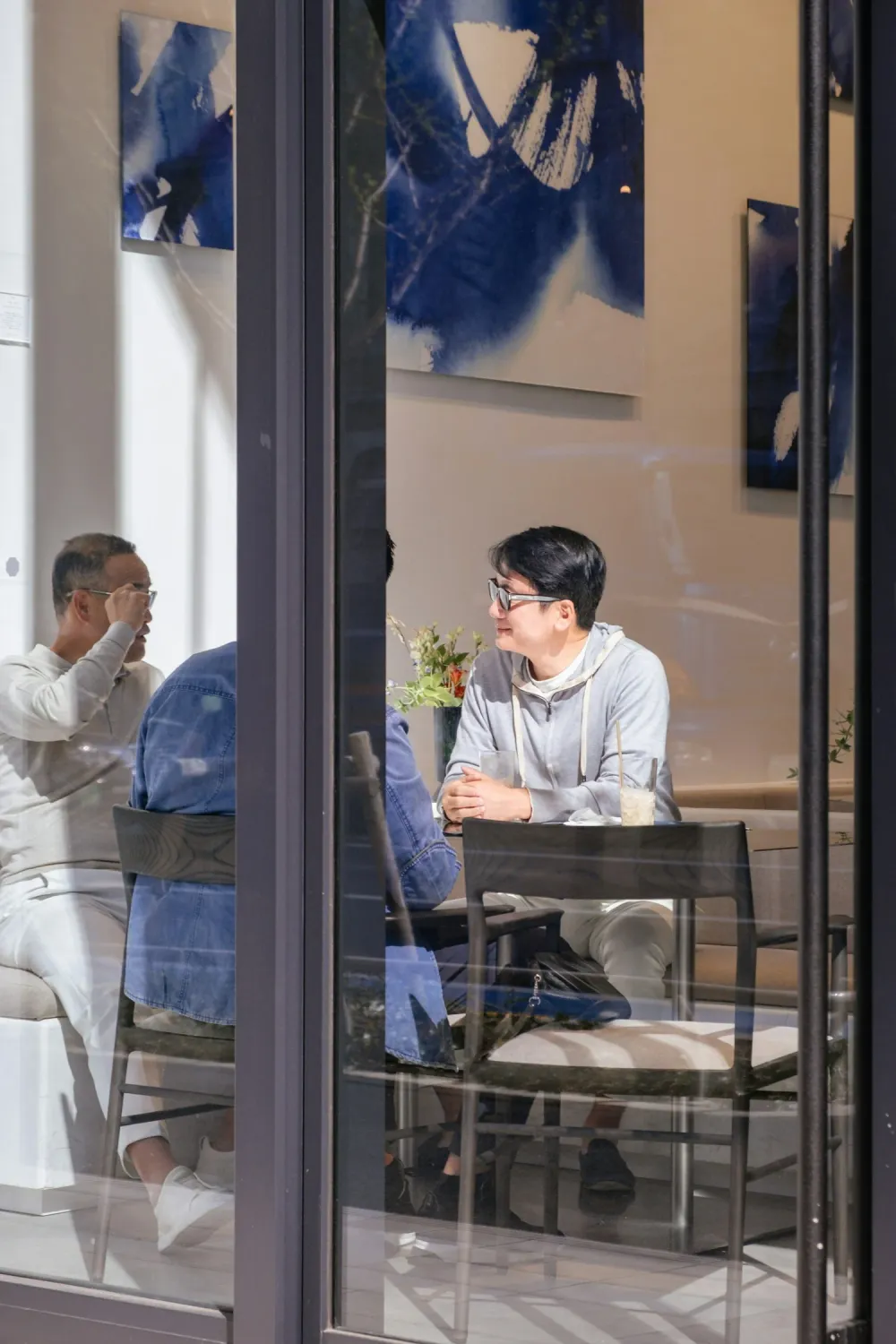 People talking at a table, photographed through a café window in Tokyo